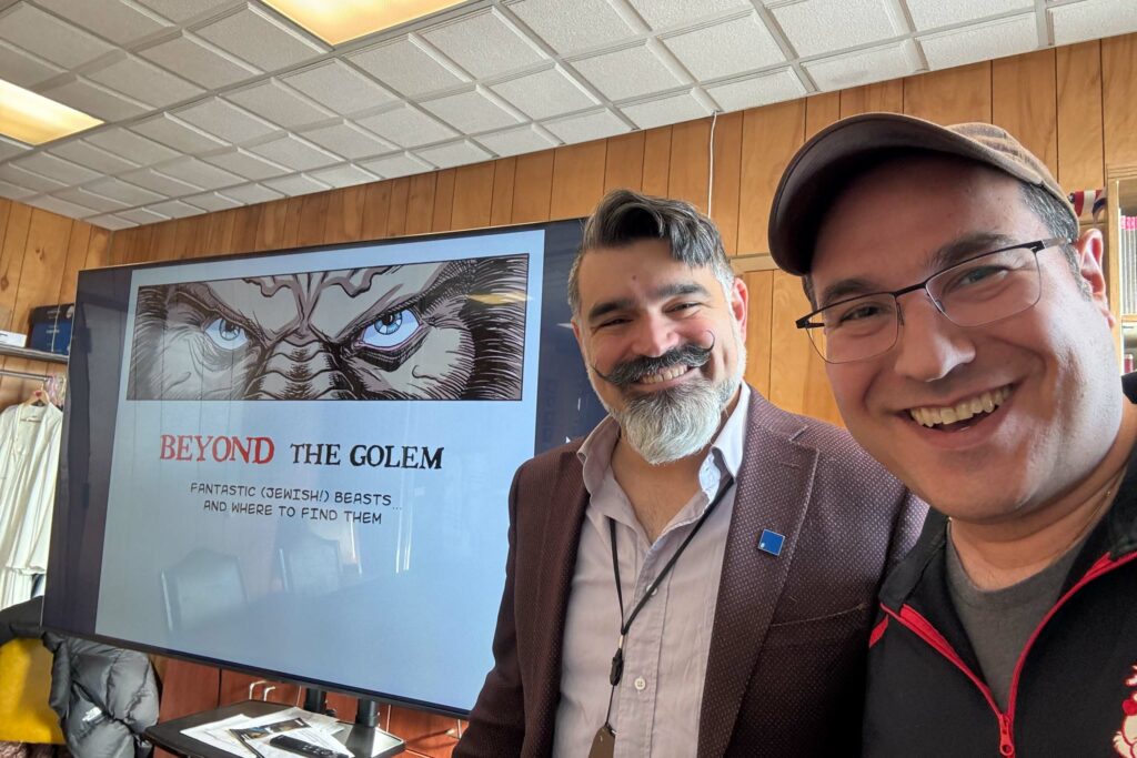 two men in front of beyond the golem presentation.